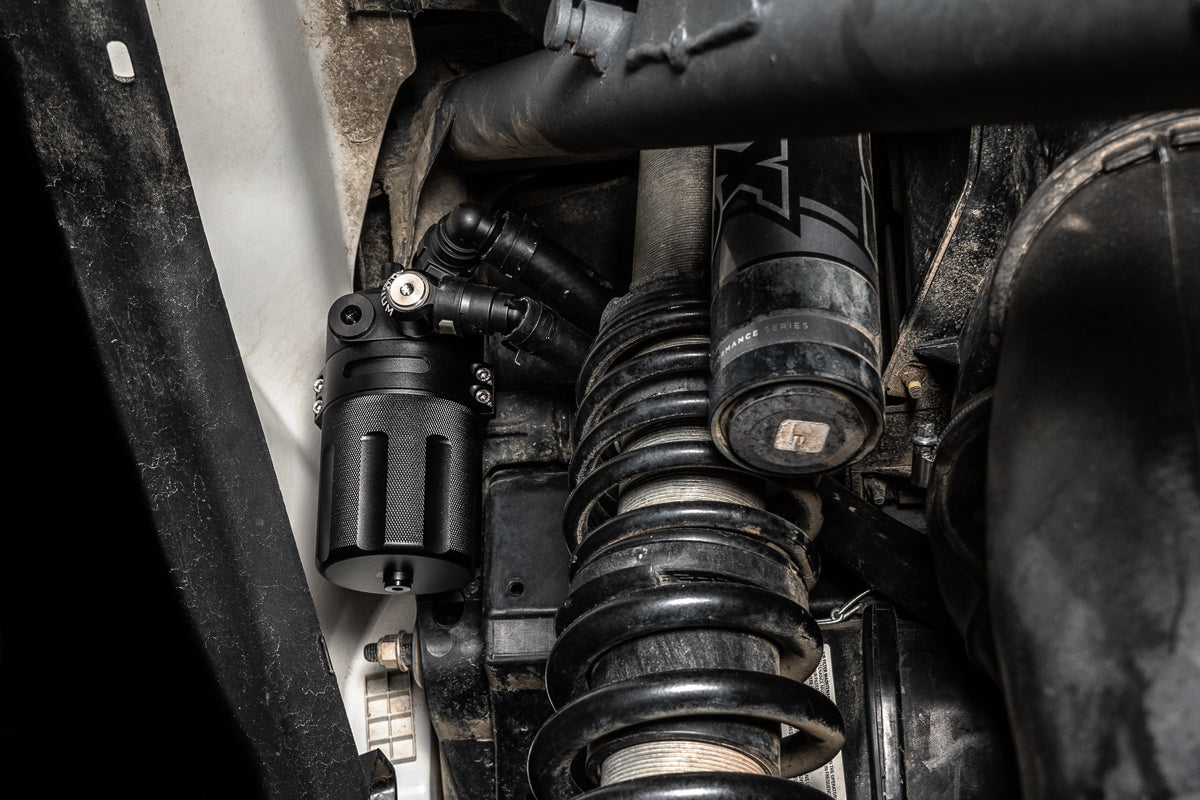 Radium catch can installed in the left rear wheel well of a Can-Am Maverick X3