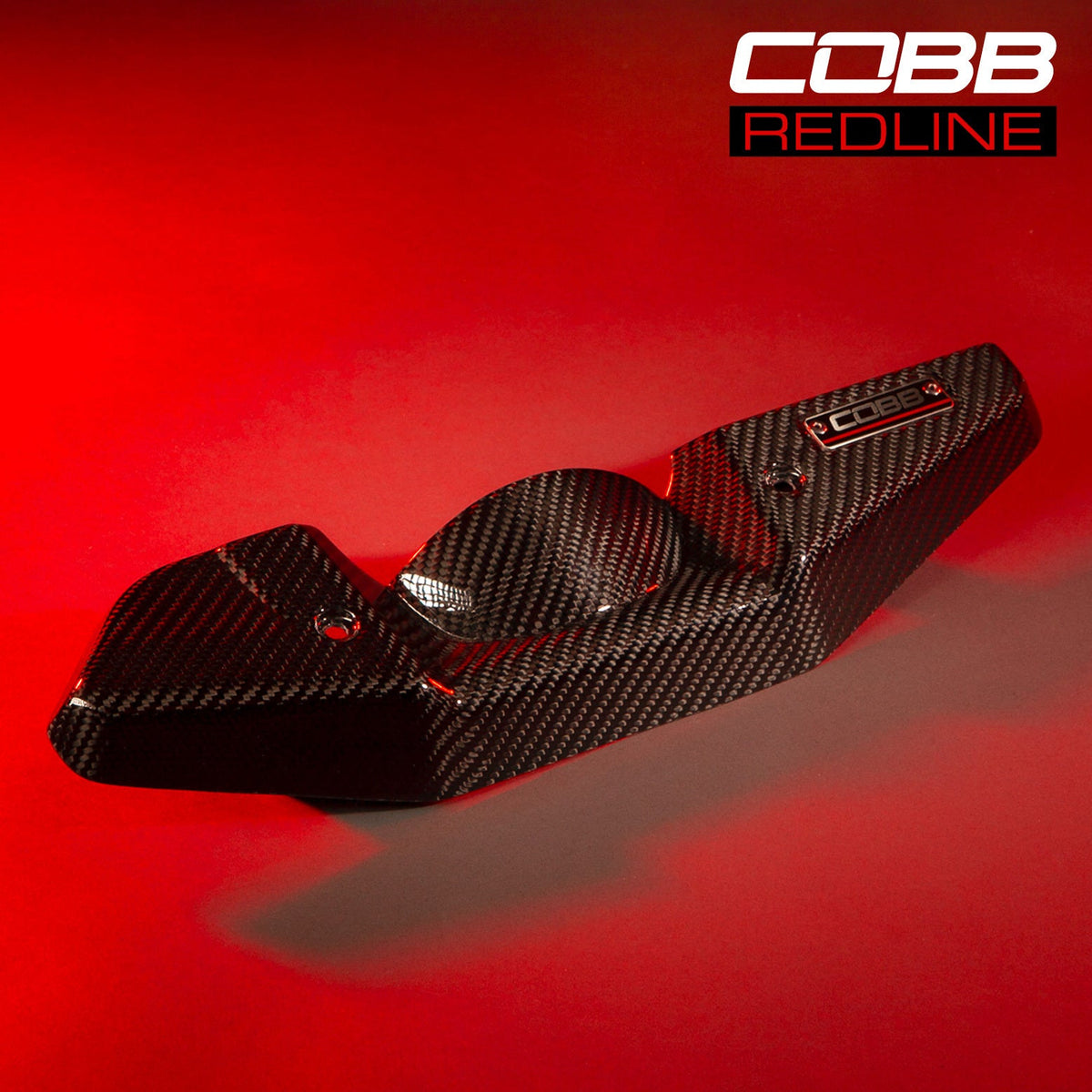 COBB Redline carbon fibre alternator cover – Subaru WRX and STI – cover on a red-lit background
