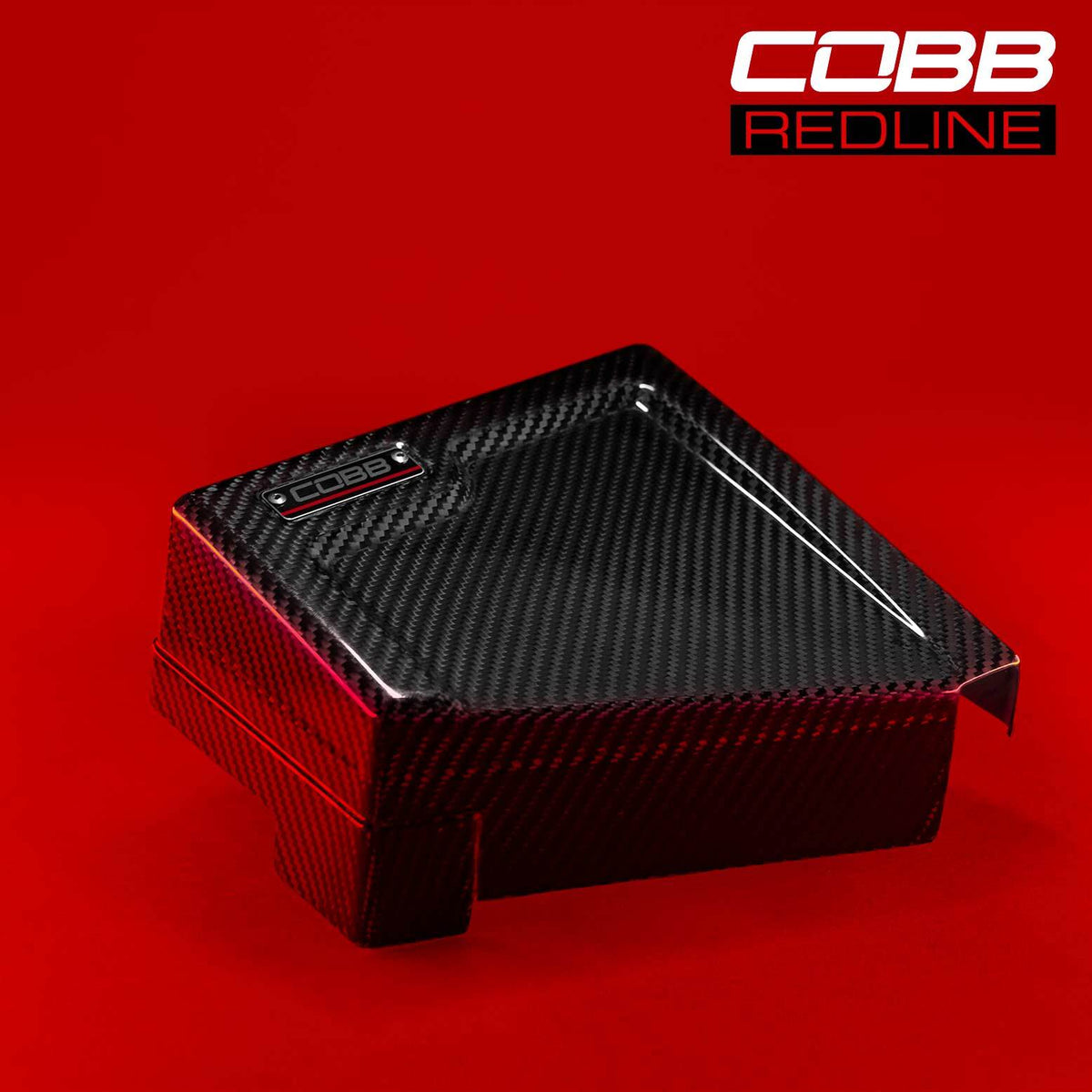 COBB Redline carbon fibre fuse cover – Subaru WRX VB – battery-side cover on red background