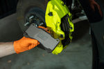 GrimmSpeed titanium front shim being fitted behind a pad in a Subaru WRX STI yellow Brembo 6-piston front caliper - GrimmSpeed Thumbnail