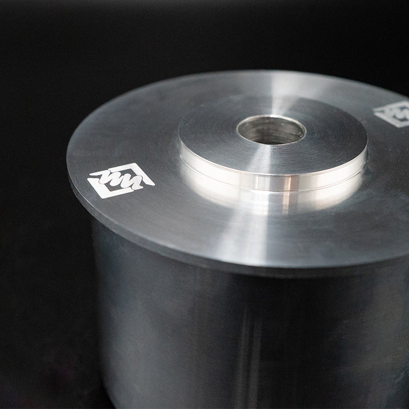 Suspension Secrets subframe bush, close-up of the flange and engraved logo on a dark background